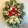 Standing floral spray with red roses and white flowers on a gold ribboned easel