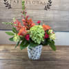 A lively cluster of coral-orange roses and bright green hydrangea makes an