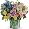 Mixed bouquet of roses, lilies, and blue flowers in a mosaic vase