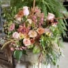 Soft peach and blush roses tumble from a classical stone urn in