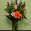 Bouquet of orange lilies and pink roses in a clear glass vase
