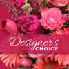Pink floral arrangement with roses and daisies behind a Designer's Choice banner