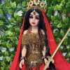 Decorative warrior doll in red-and-gold costume with jeweled crown, veil, and ornate