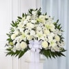 White floral spray with lilies and chrysanthemums in a vase, tied with a white ribbon