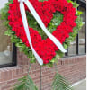 Heart-shaped red rose standing spray with a white ribbon