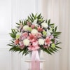 Pink and white floral spray with a ribbon bow on a stand