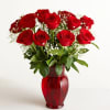 Red roses arranged in a red glass vase with baby's breath