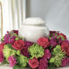 This urn arrangement has fuchsia,
 stock, hot pink roses, green chrysanthemums, green