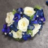 A wrist corsage of white spray roses, dark blue belladonna, dark blue