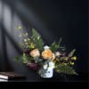 Peach and white roses in a white vase with yellow accent flowers