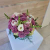 Low round arrangement of lavender roses with white blooms in a clear glass bowl vase