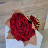 Large bouquet of red roses wrapped in brown paper and tied with a red ribbon