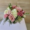Low arrangement of pink roses and white hydrangeas in a clear glass vase