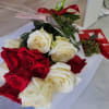 Bouquet of red and white roses with a red ribboned gift box on a white surface