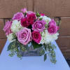 Low arrangement of pink roses and white hydrangeas in a clear glass cube vase