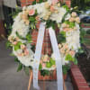 Standing wreath of white mums and peach roses with ribbon on wooden easel