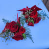 Two red rose wrist corsages with gold bead accents and ribbon on a light blue surface