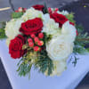 Low arrangement of red and white roses with white hydrangeas, berries, and evergreen accents