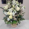 Tall basket arrangement of white roses and white blooms with small blush accents