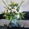 Large white and green floral arrangement with roses, lilies, and snapdragons in a white vase