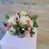Low arrangement of pink roses, white hydrangeas, and lilies in a clear glass bowl vase