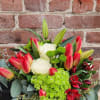 Mixed arrangement of red tulips, white roses, green hydrangeas and lilies in a clear glass vase
