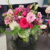 Mixed pink and white flower arrangement with trailing greenery in a white pot on a black table