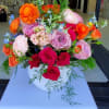 Colorful arrangement of roses and ranunculus in a white bowl-shaped vase
