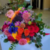 Colorful hand-tied bouquet of roses and mixed blooms in bright pink, orange, yellow, and purple tones