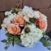 Low arrangement of peach roses and white hydrangeas in a round vase
