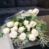 Hand-tied bouquet of white roses wrapped in clear cellophane on a black table