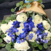 Bouquet of white roses and bright blue orchids wrapped in gold paper