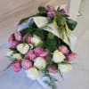 Bouquet of pink and cream roses wrapped in white paper with a satin ribbon bow