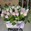 Dense cluster of pink, white tulips in a white woven basket finished