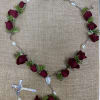 Rose petal rosary with silver beads and a crucifix on burlap