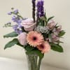 Mixed bouquet of pink and purple flowers in a clear glass vase