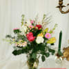 Mixed bouquet of roses, lilies, and pink daisies in a glass vase