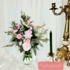 Pink floral arrangement in a clear glass vase beside a green candle holder