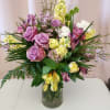 Lavender roses and yellow flowers arranged in a glass vase