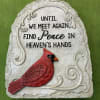 A bright red cardinal perched on a pale, textured memorial stone creates