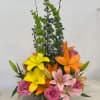 Colorful mixed bouquet with lilies and roses in a low vase