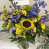 Bouquet with a sunflower center, purple and yellow flowers in a glass vase