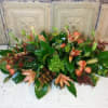 Low floral centerpiece with peach blooms and green foliage