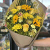 Yellow mixed bouquet wrapped in brown paper with a ribbon