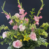 Pink roses and gladiolus in a glass vase with yellow lilies