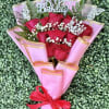A tight cluster of vivid red roses wrapped in soft pink paper