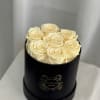 Cream roses arranged in a black round box
