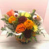Halloween bouquet in a pumpkin container with roses, marigolds, and eyeball picks