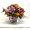 Bouquet of purple and orange flowers in a white mug