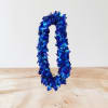 Blue floral lei on a light wood surface